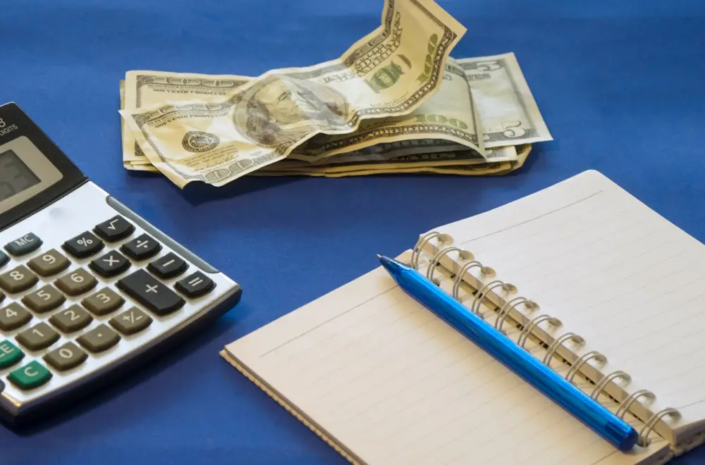 US dollars, a notebook and a calculator on a blue background