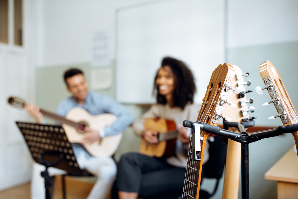 Young man and woman playing guitar during rehearsal in recording studio.