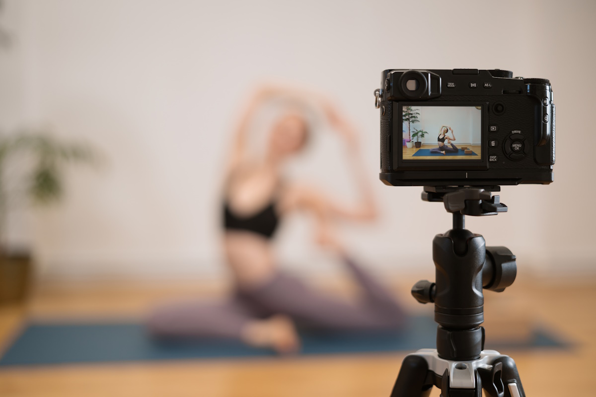 Sporty young woman doing yoga practice on white wall background with plants - concept of healthy life and natural balance between body and mental development